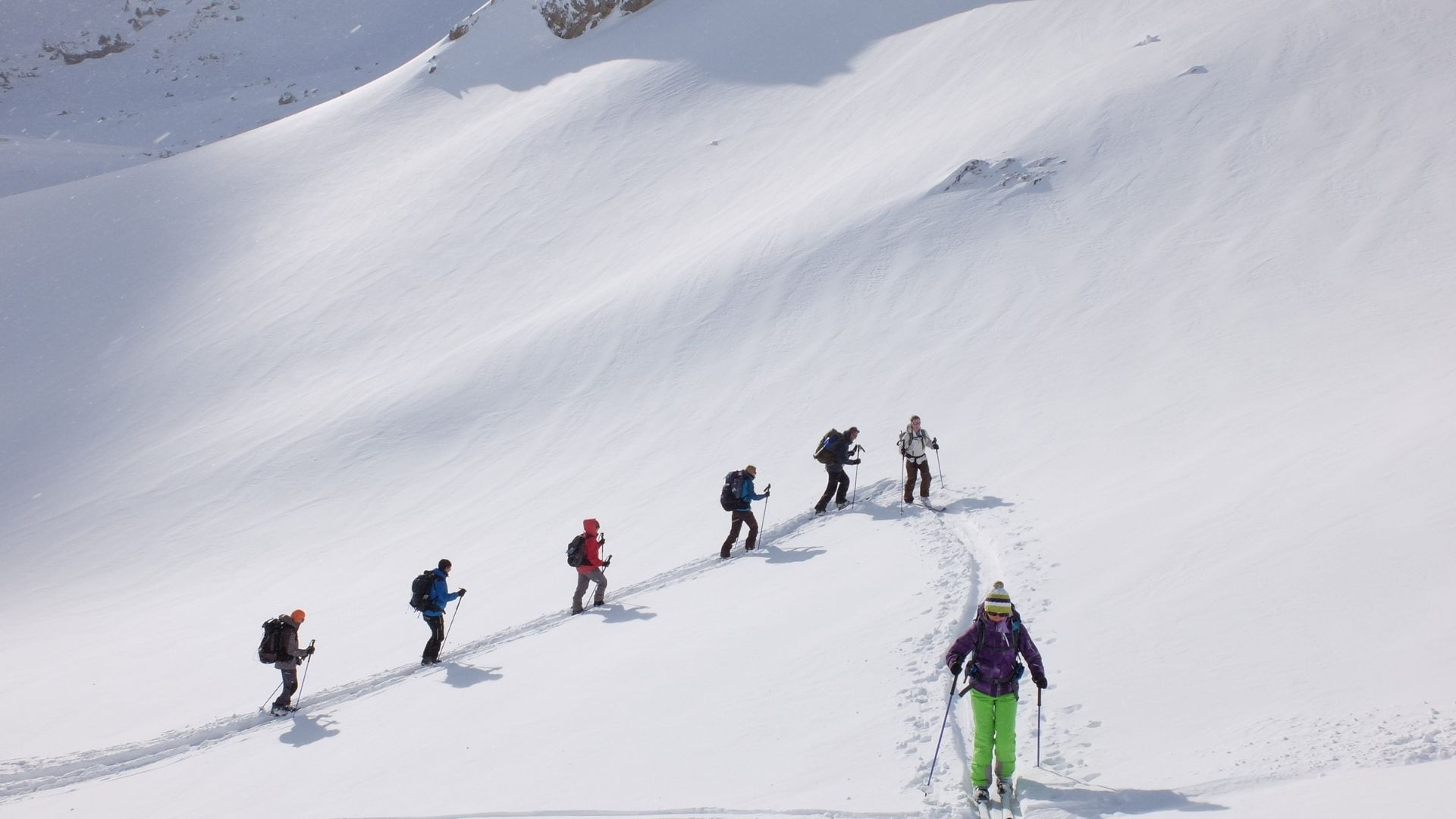 Groupe en ski de randonnée montant une pente enneigée - Alpes