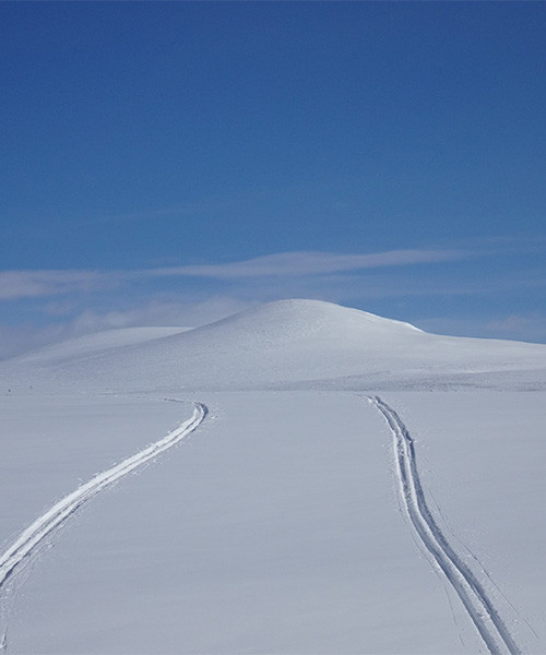 Traces de ski sur un plateau enneigé vers un dôme blanc