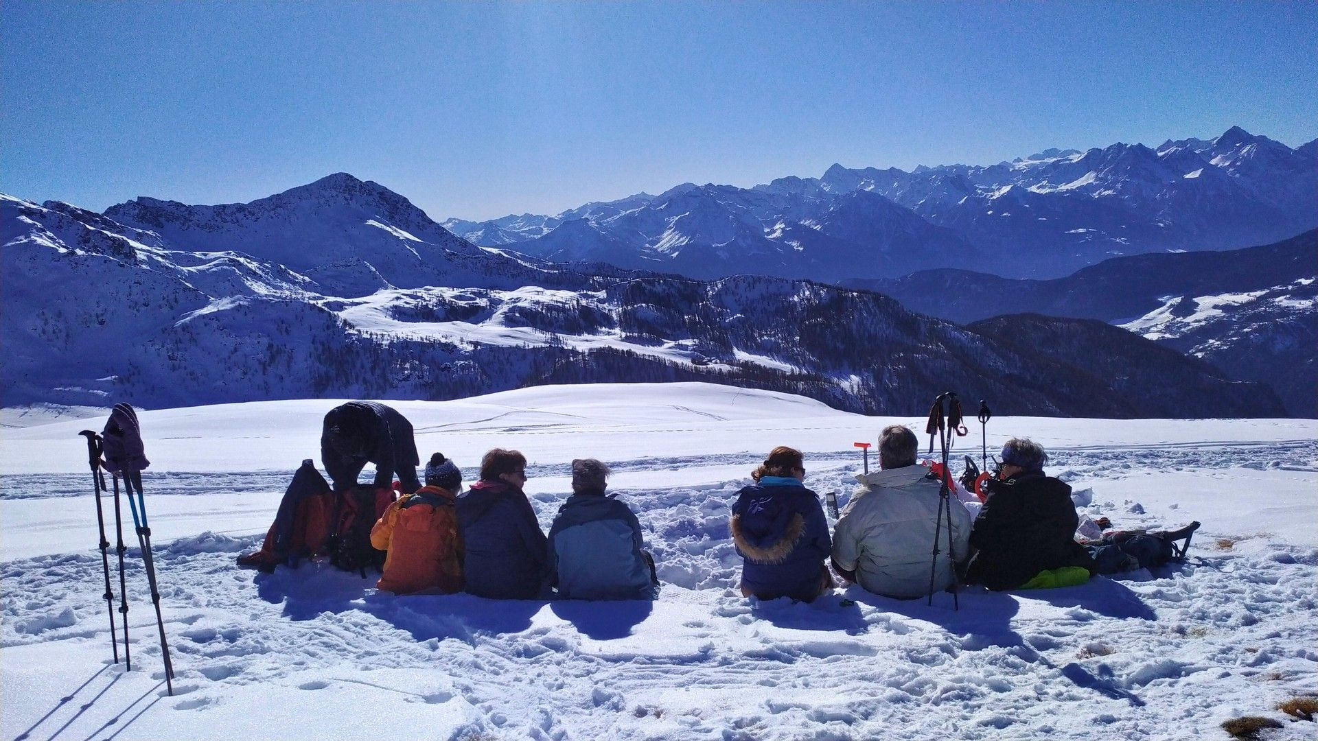 © Pierre Paillat Pause d'un groupe en raquettes face aux sommets enneigés - Valais - Suisse
