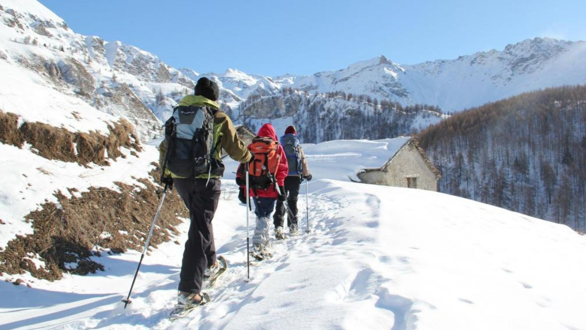 Randonneurs en raquettes vers un hameau enneigé - Alpes italiennes - Italie