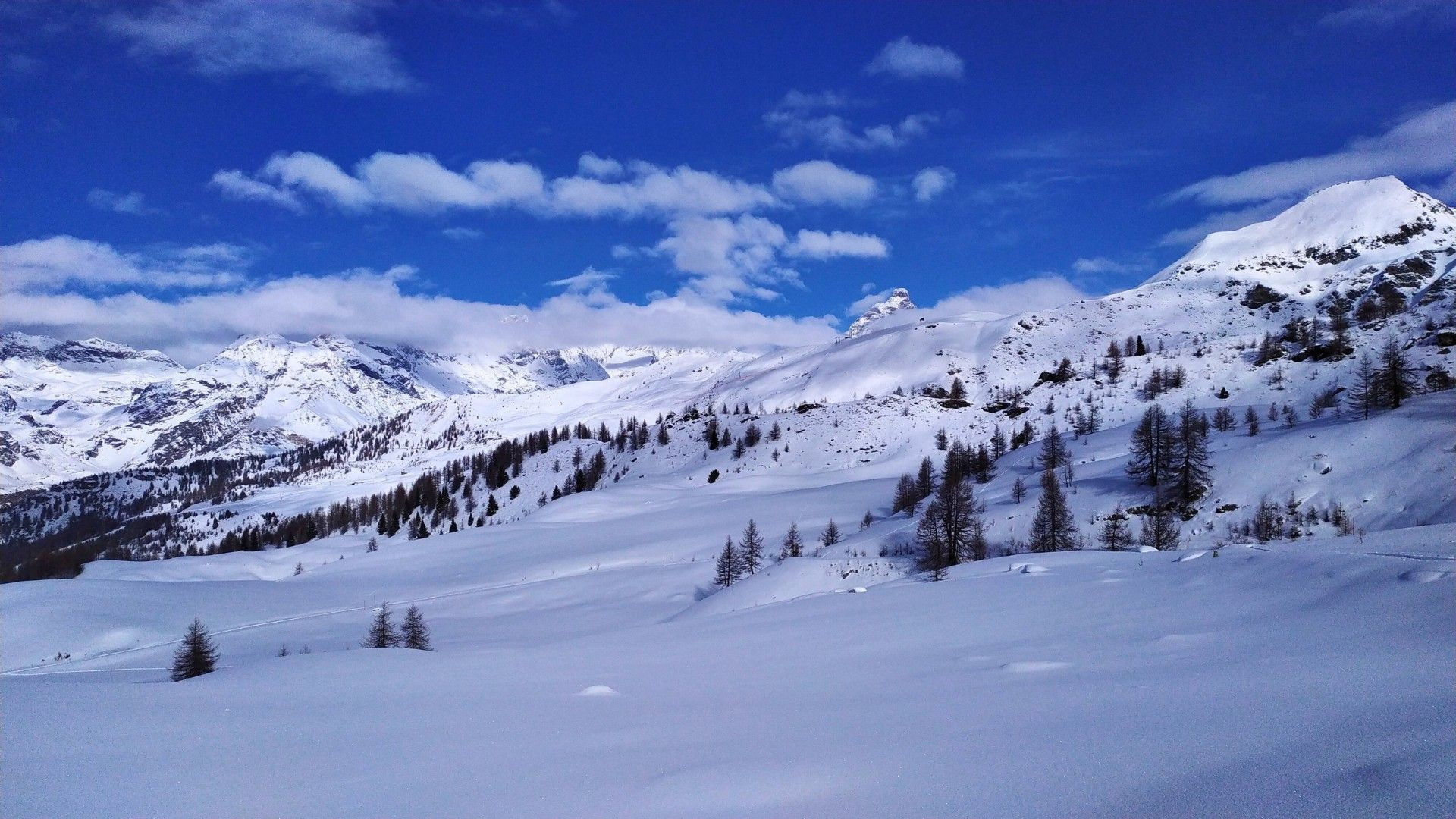 © Pierre Paillat Panorama de montagnes enneigées sous un ciel bleu - Alpes