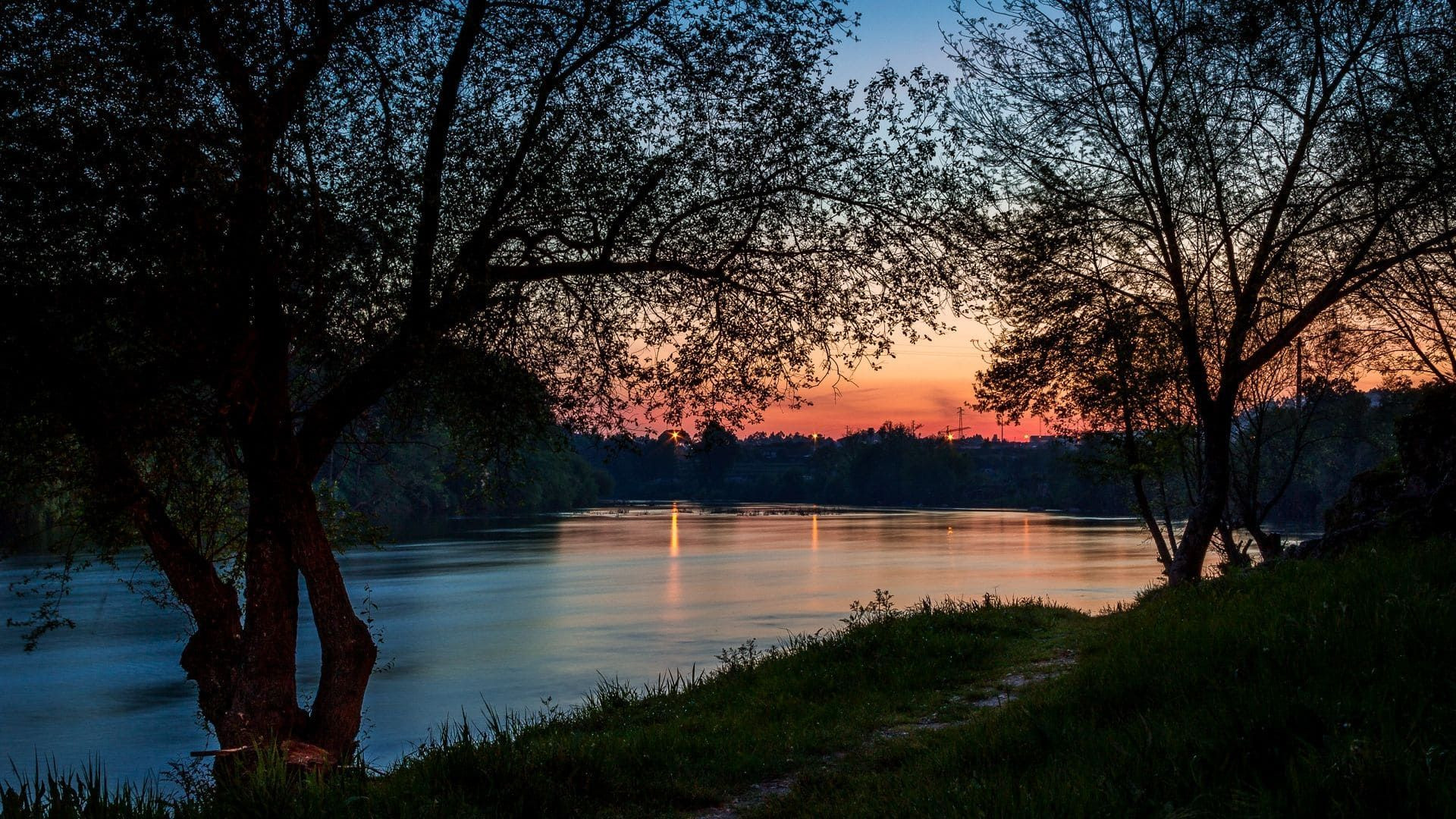 Coucher de soleil sur une rivière bordée d'arbres - Portugal