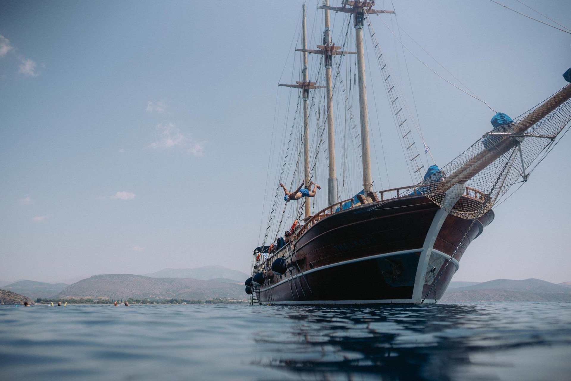 Goélette traditionnelle au mouillage et baigneurs - mer Égée - Grèce