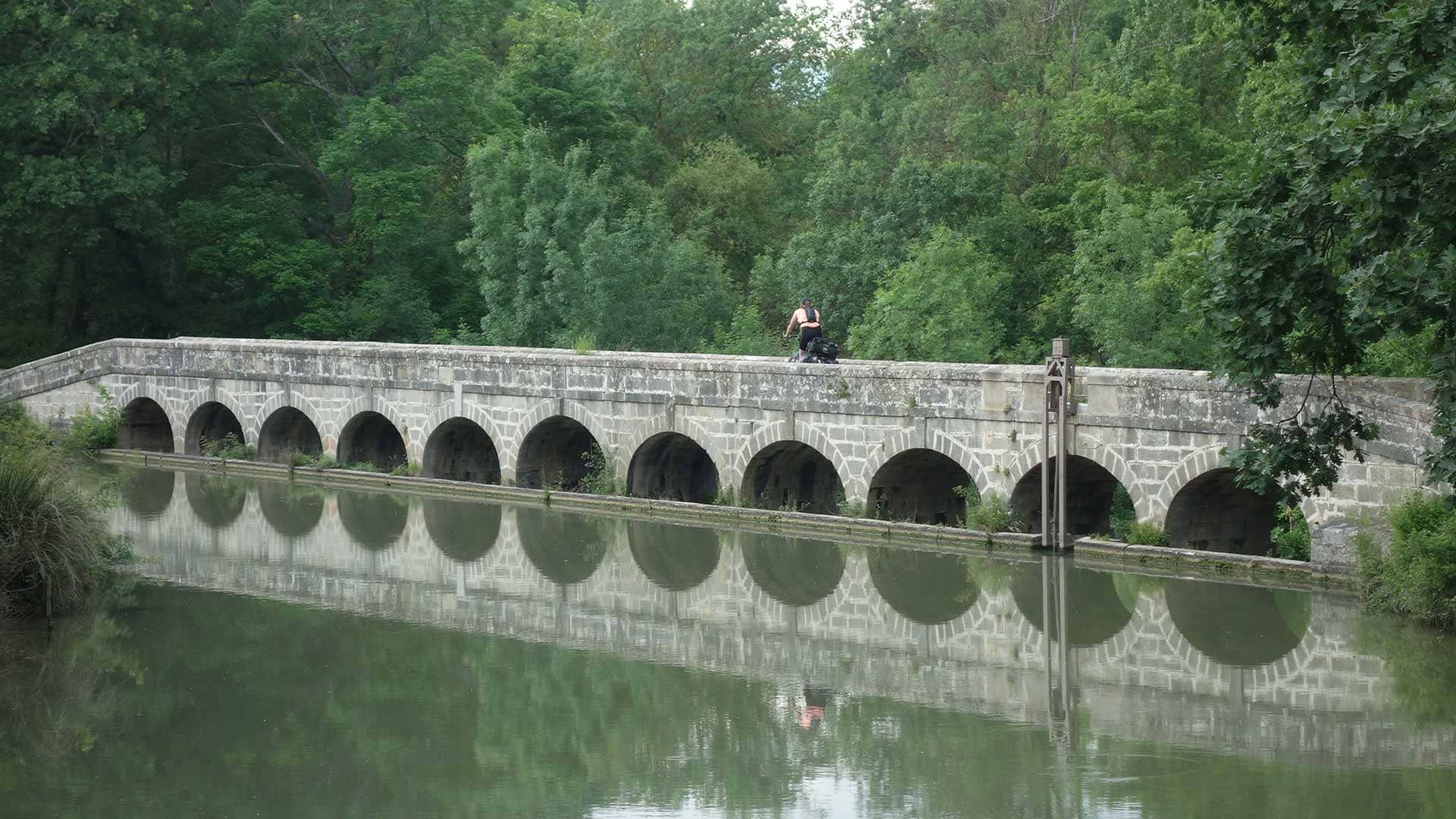Cycliste sur un pont-canal en pierre - Canal du Midi - France