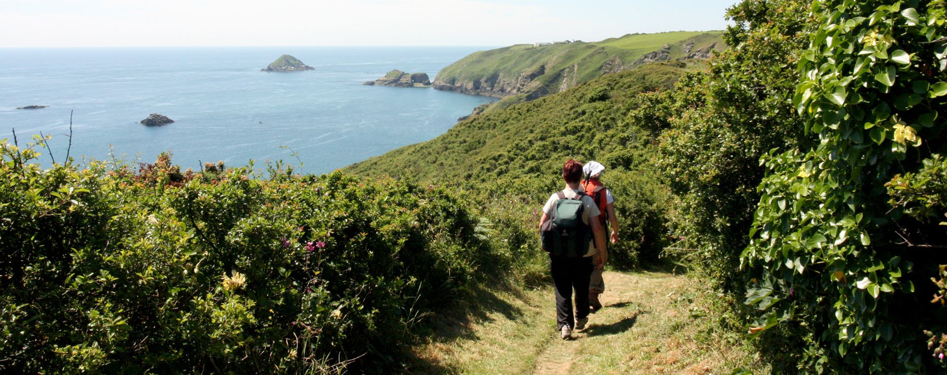 Randonneurs sur sentier côtier au-dessus de la mer - Îles Anglo-Normandes