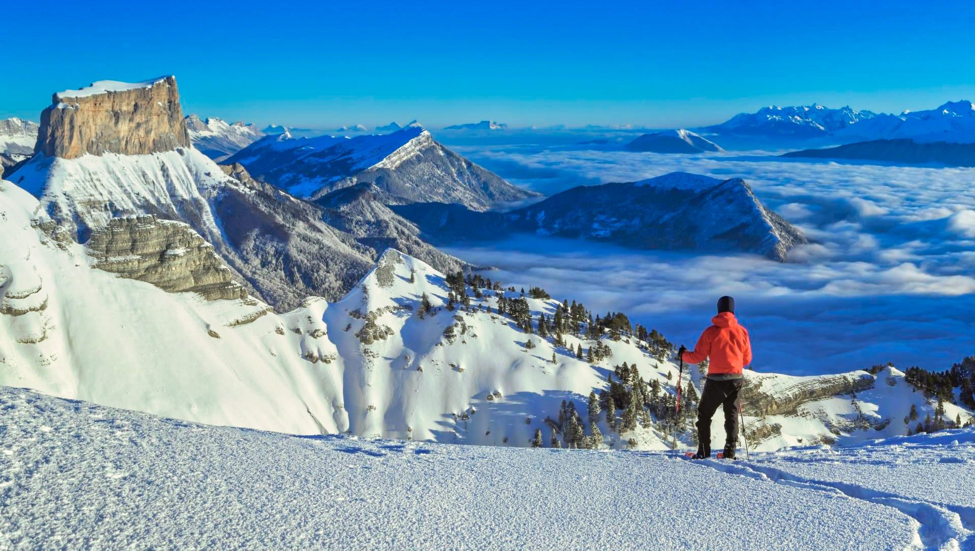 © Adobe Stock Randonneur en raquettes face au Mont Aiguille et mer de nuages - Vercors - France